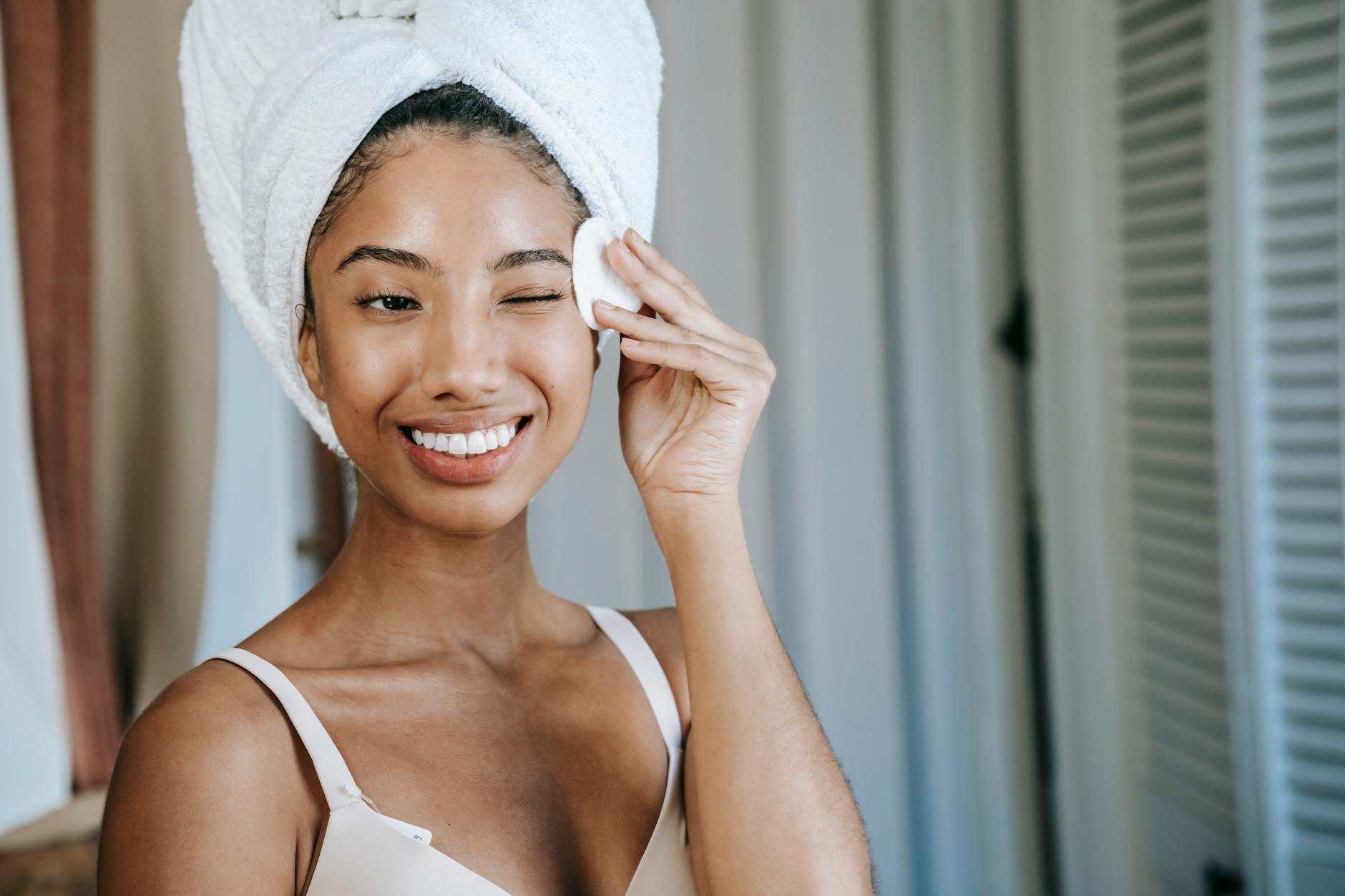 smiling ethnic woman using face cleanser and face wash in the morning